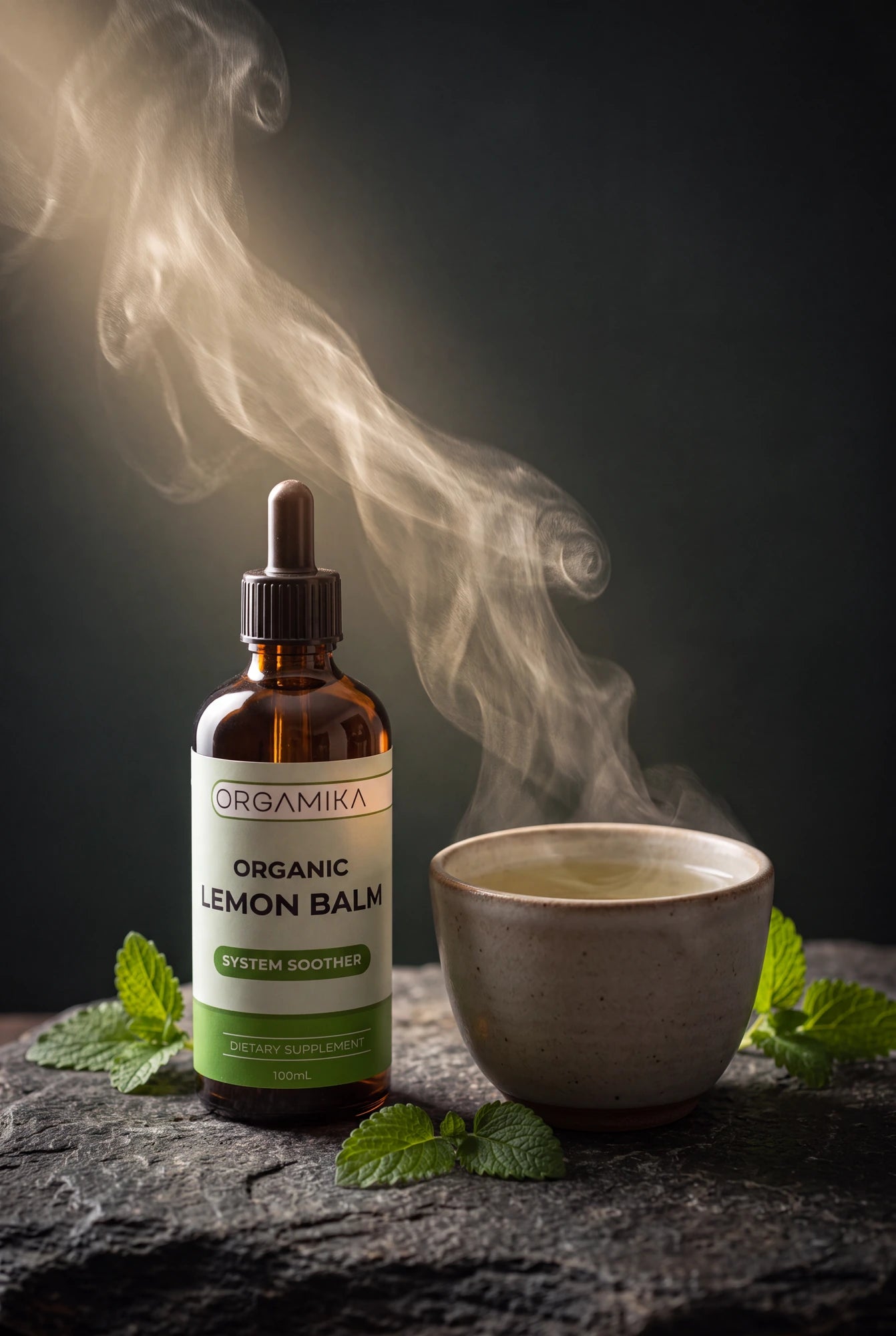 ORGAMIKA Organic Lemon Balm bottle beside a steaming cup and fresh lemon balm leaves on dark slate